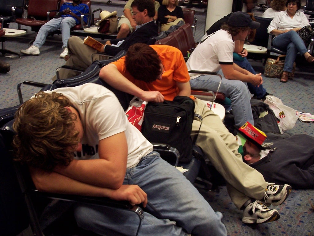 Fotografía de viajeros cansados en aeropuerto. Startups prometen solucionar esta sicuación.
